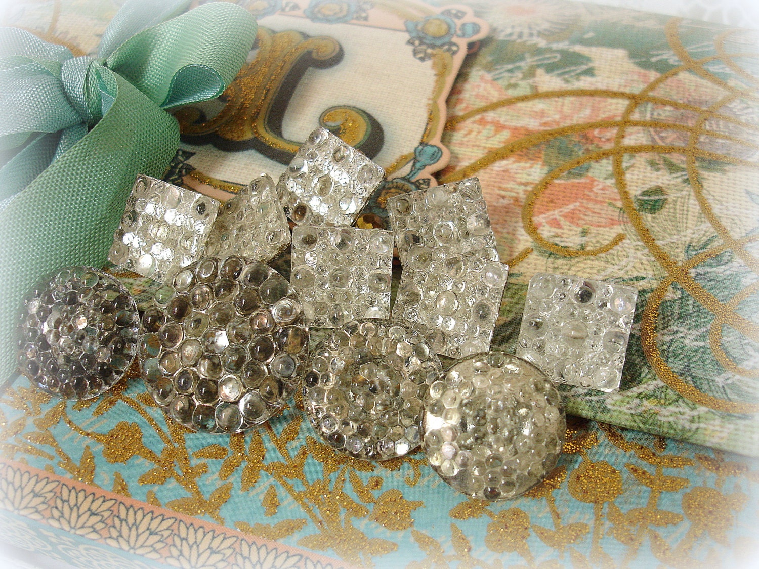assorted vintage foil backed glass buttons . crystal clear pressed glass with gold foil backs . shanks . bumpy texture
