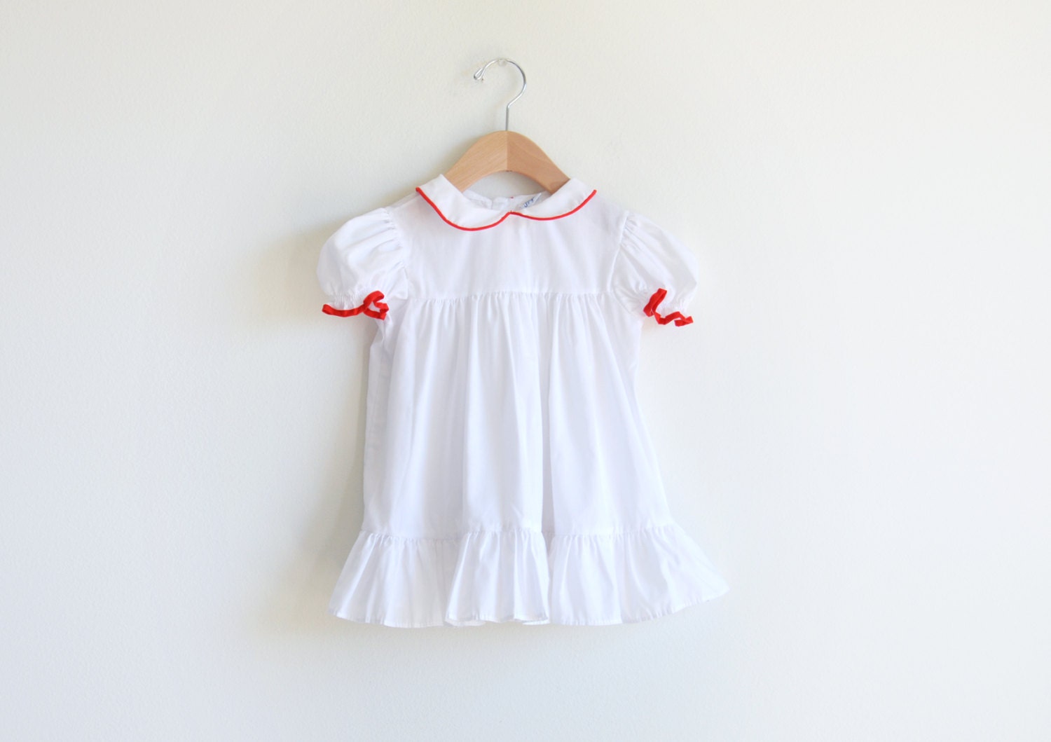 Vintage white toddler girl's dress with red trims.