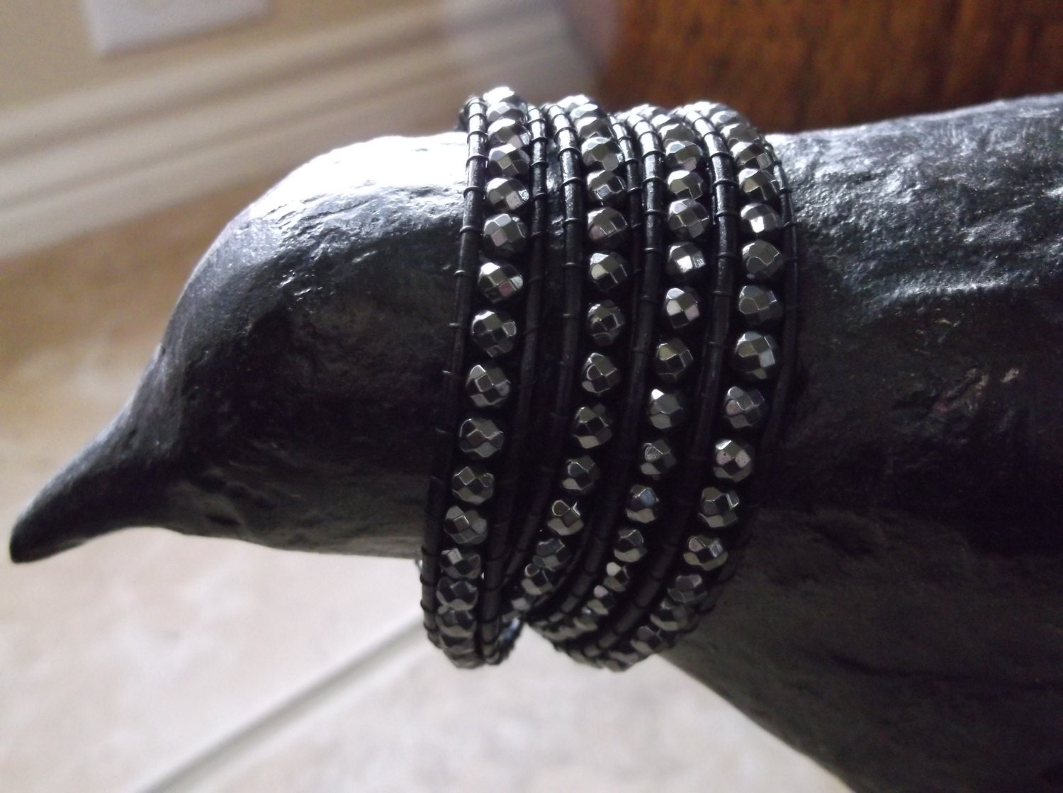 Chan Luu inspired 4 wrap bracelet made with faceted hemitite beads on black leather and finished with a silver button.