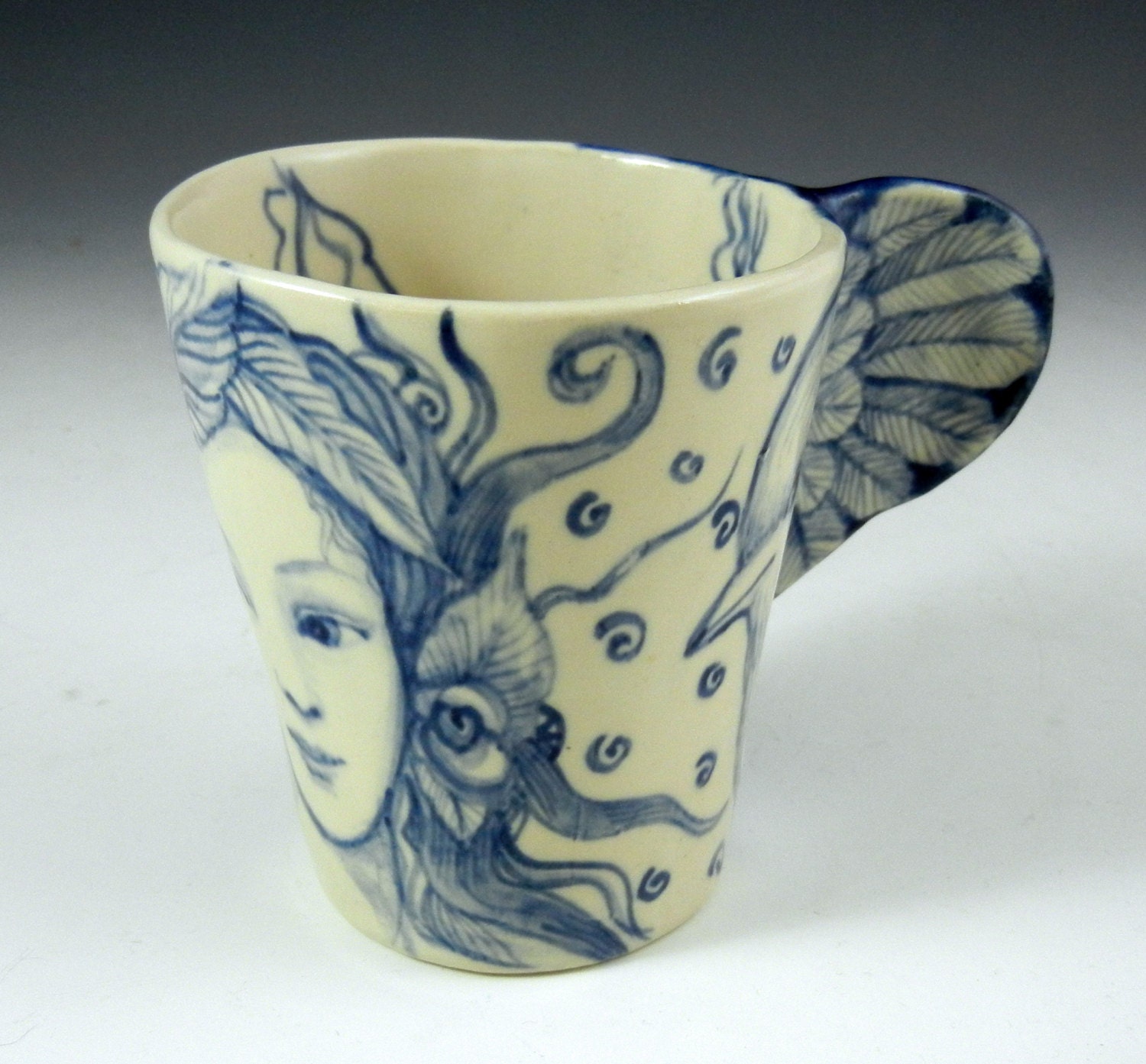 Hand made blue and white coffee or tea cup with bird wing and face