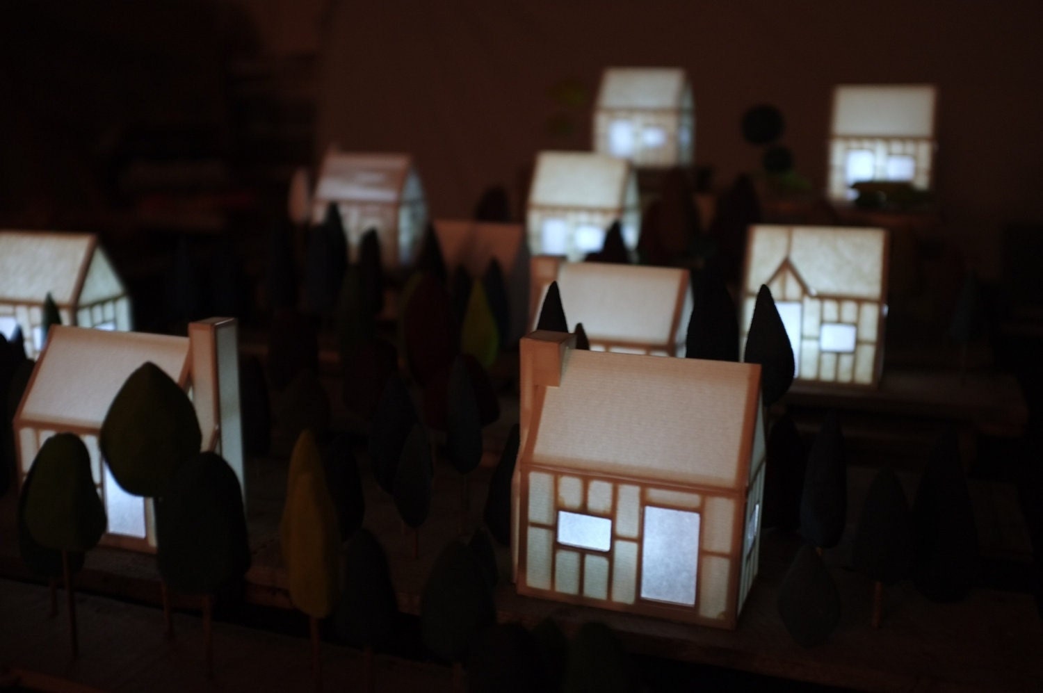 Paper and wood miniature glowing house with tiny hand carved trees