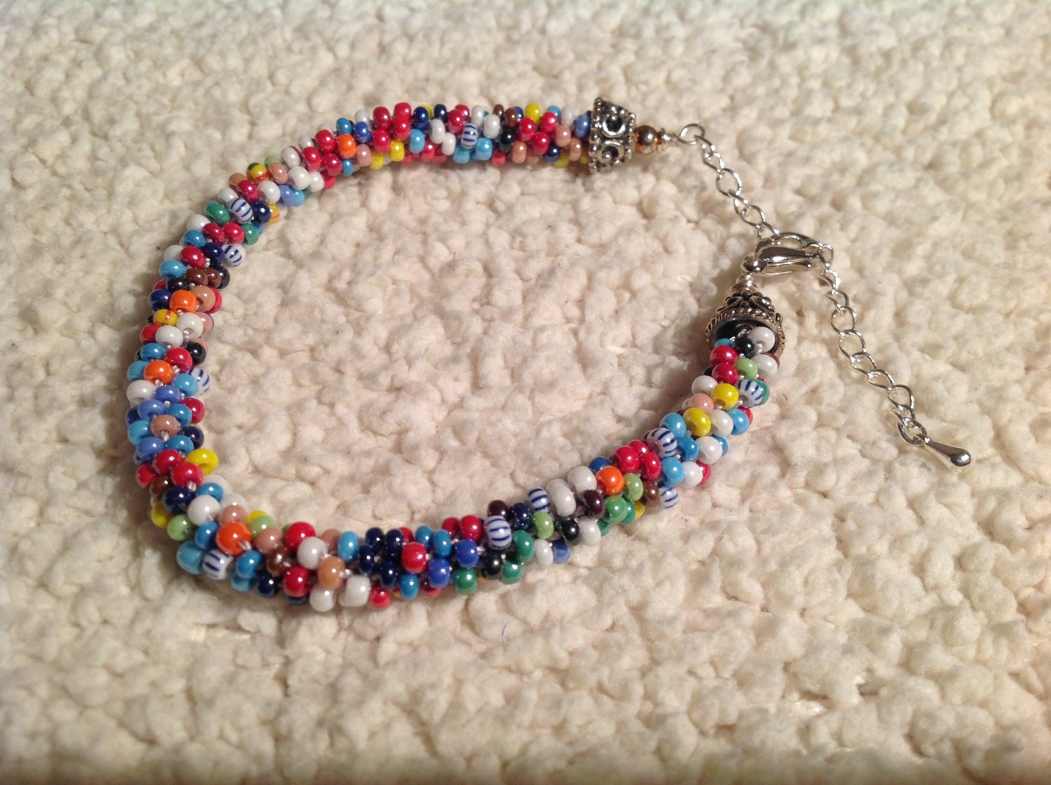 Thin pearl toned rainbow colored glass beaded kumihimo bracelet with silver findings and chain to adjust the length