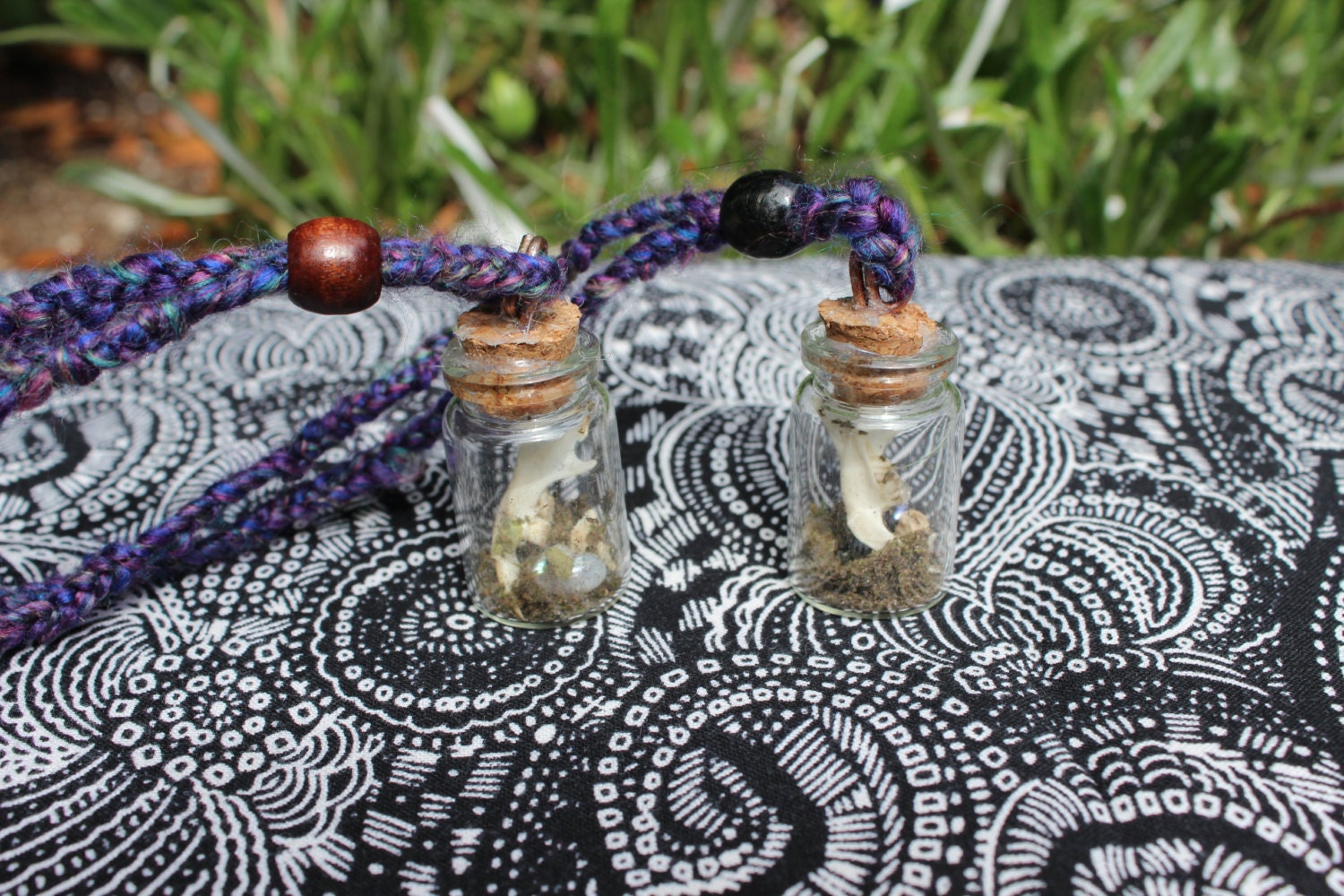 Terrarium style necklace pendant containing small animal bones, moss, and pearls.