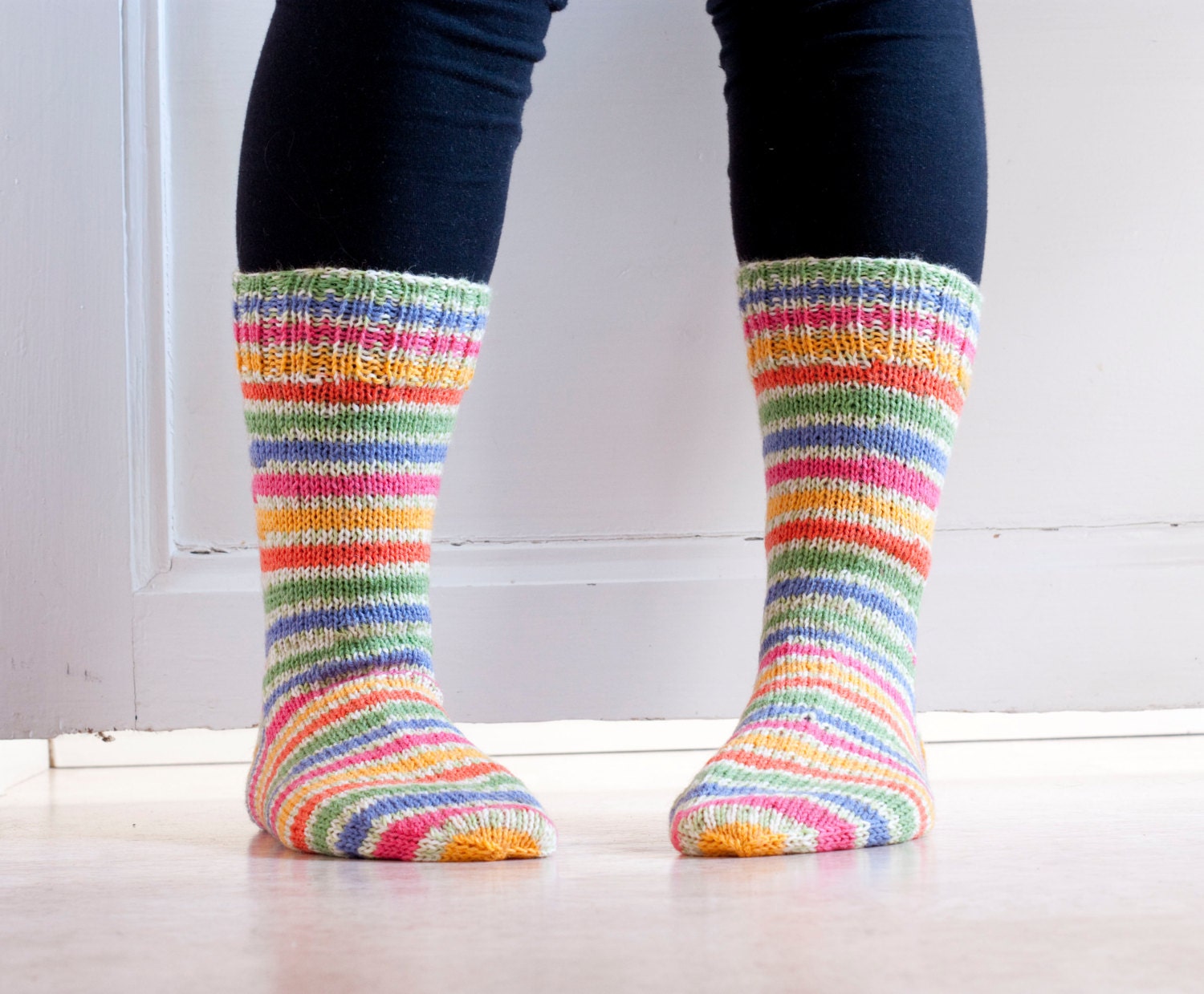 Hand knit socks in durable woolblend yarn in colorful stripes in pink, blue, green, yellow, orange. Floral meadow.