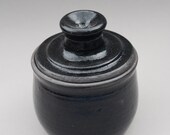 black lidded jar with purple plum inside