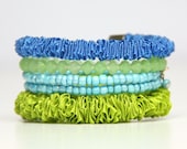 Stackable bracelets set. A set of four bracelets in shades of green and blue made of ruffled ribbon and beads. Colorful and playful