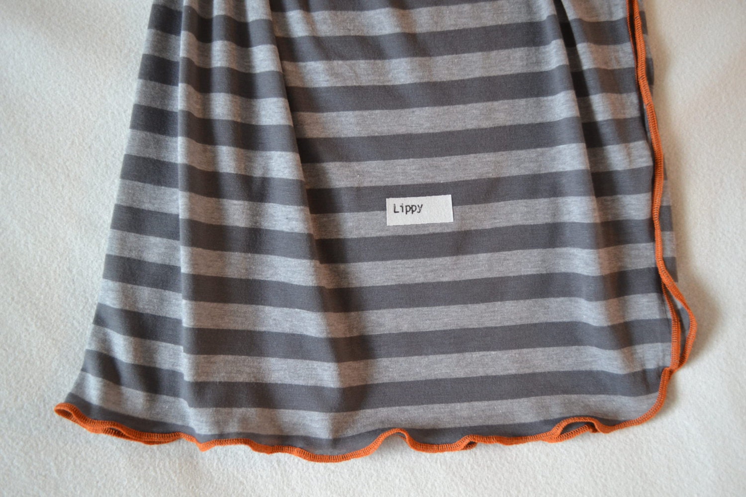 Swaddling blanket.  Size 31 by 40 inches.   Colors- gray and light gray with orange edging.   Made by lippy brand.
