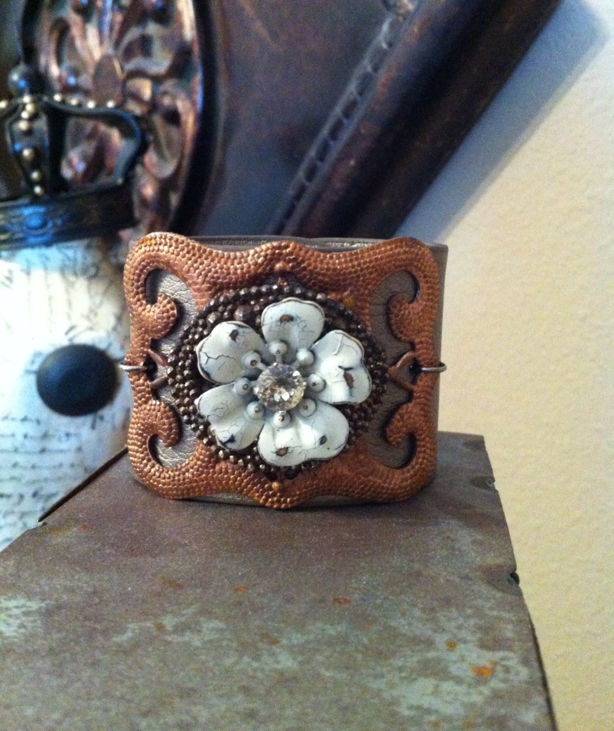 Leather cuff bracelet with copper buckle and aged metal flower.