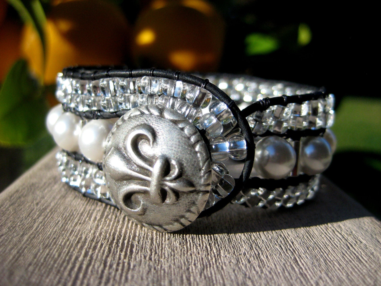 Swarovski pearls , Czech glass beads in clear with a silver lining , black leather , fleur de lis button