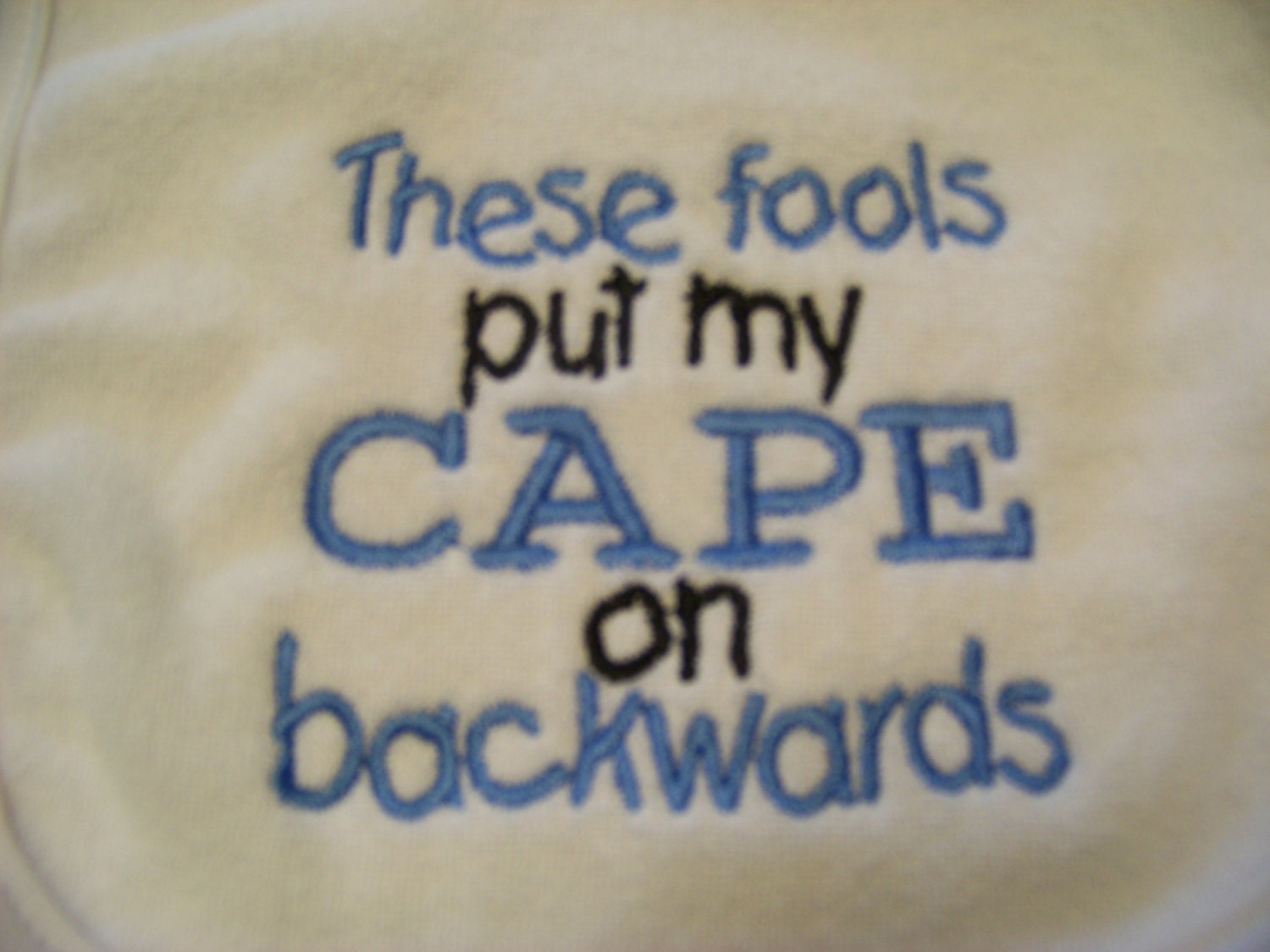 Baby Boy Bib - These fools put my CAPE on backwards   baby blue/black thread