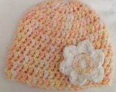 Light pink, yellow, and white handmade crochet baby hat with small white flower appliqué