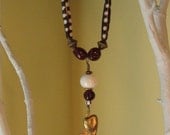 Beaded necklace with brass maple seed pod on waxed cotton cording