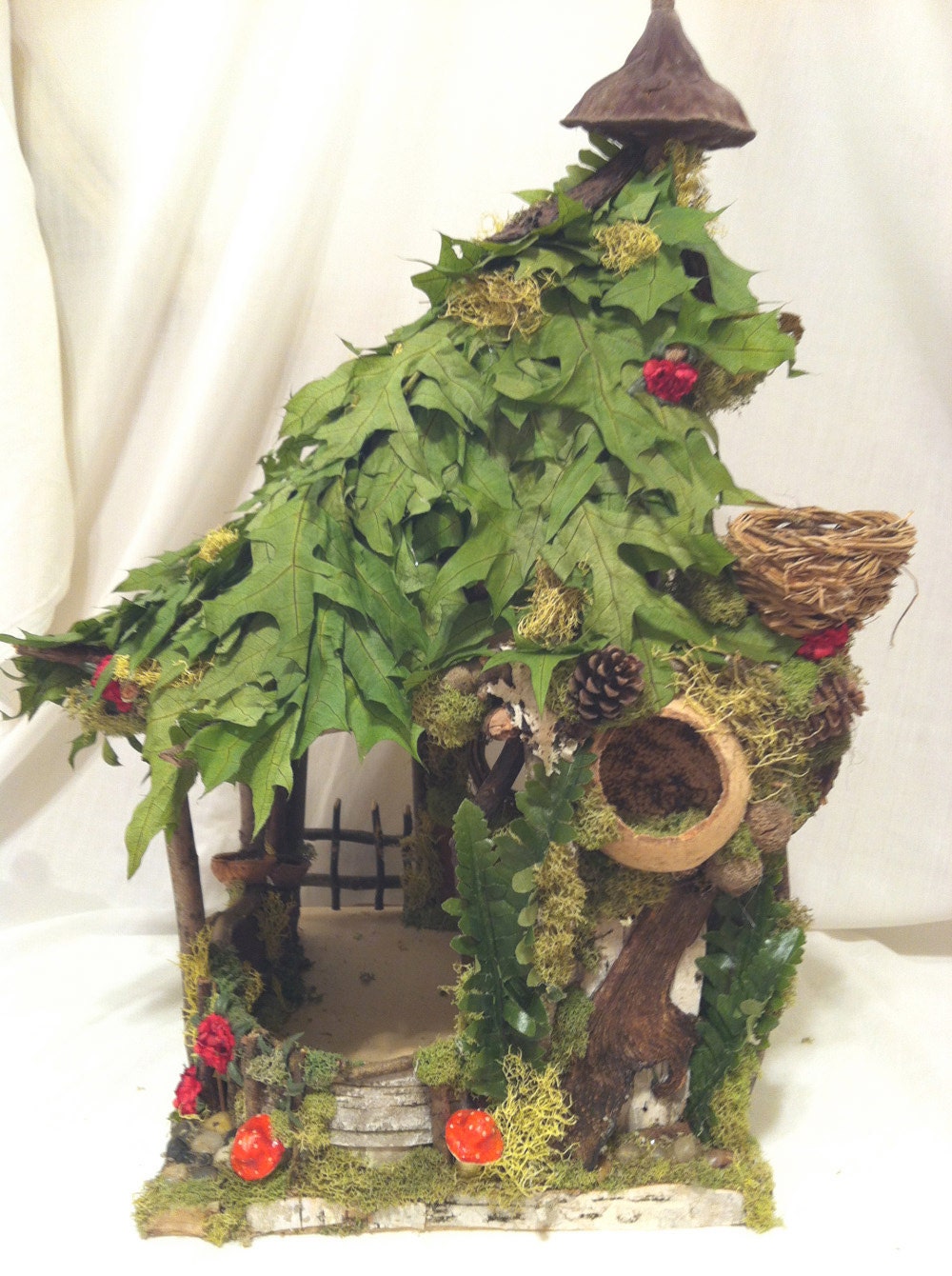 Leafy fairy or gnome house with red amanita mushrooms and birch bark