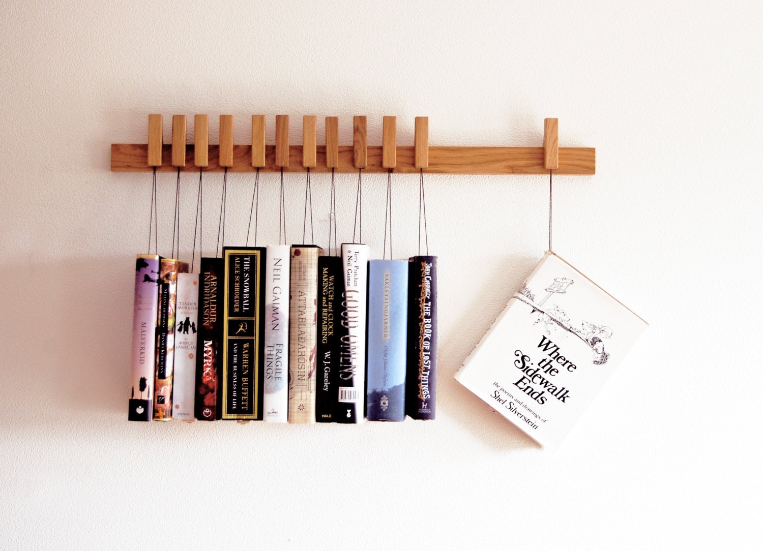 Custom made wooden book rack / bookshelf in Oak. The pins are also bookmarks.