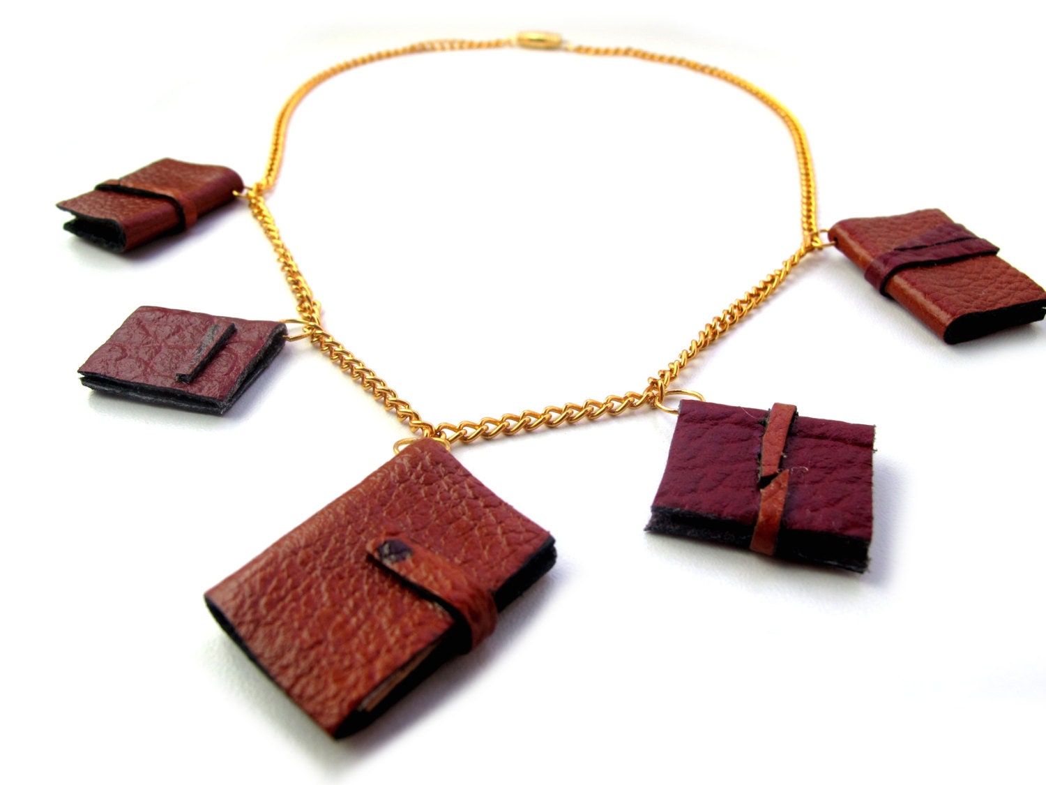 Book necklace, five brown and tan decorative leather journals on gold chain.