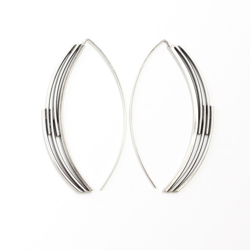 Pieces of silver woven together in a long arc shape to create an artistic and modern earring design - "Interlace Earrings"