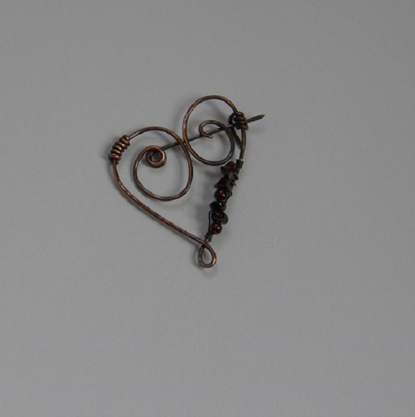 A hand forged copper heart pin.