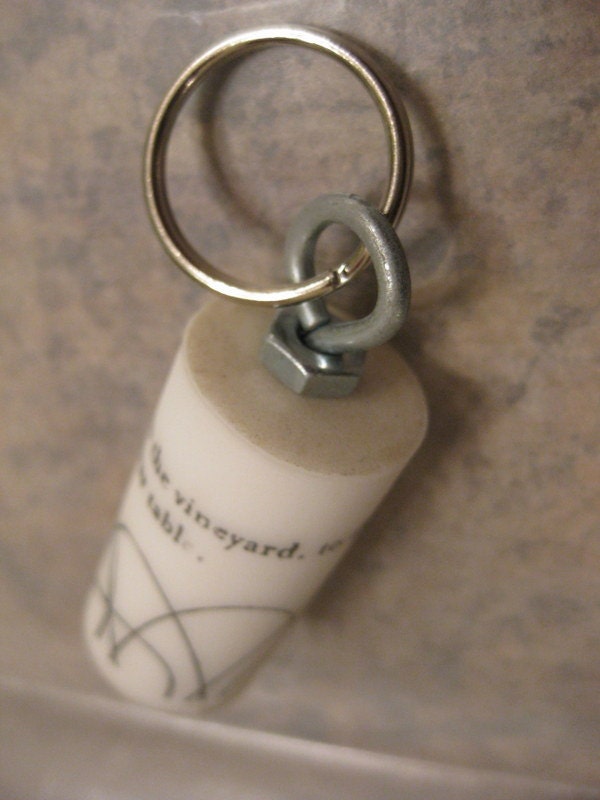 From the Vineyard to the Crusher to your Table upcycled white synthetic wine cork key chain with black logo and industiral accents