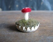 Felted amanita mushroom in a cream-colored bottlecap