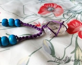 kai. netted quartz crystal necklace with wooden turquoise beads and purple thread.