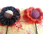 A set of two orange and grey crochet flower hairpins with fabric buttons