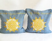 Decorative sun pillow bookends made from upcycled denim filled with dried beans. Hand-embroidered you are my sunshine.