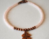 Lucky charm. Soft pink seed bead friendship bracelet with copper four leaf clover charm.