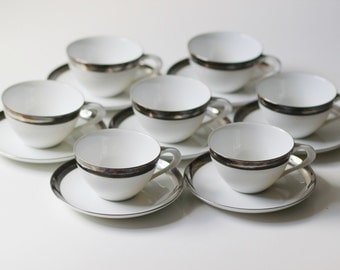 set of 7 teacup and saucers by Wincraft Saturn pattern white with platinum band excellent cond.
