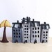 Four grey buildings of felt, with a tree. Miniature. Decoration.