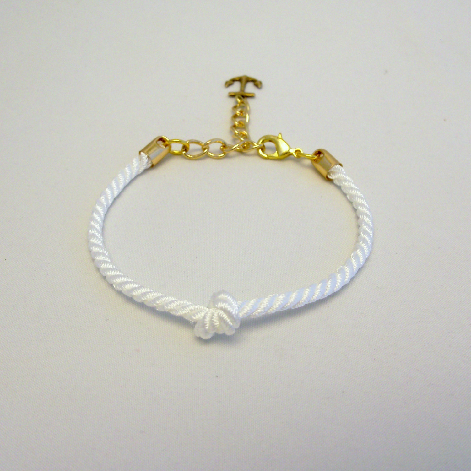 Delicate adjustable nautical knotted white rope bracelet with gold anchor or ship wheel charm