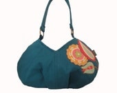 Small shoulder handbag constructed in teal blue with applique embellishment