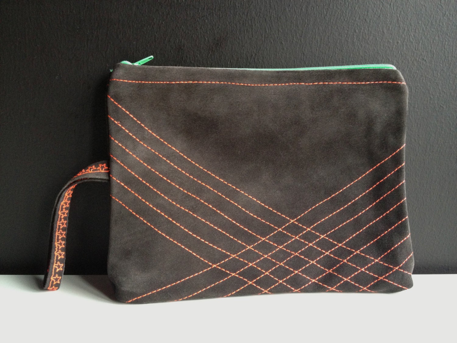 colorful leather clutch with strap and stitched geometric lines in neon pink