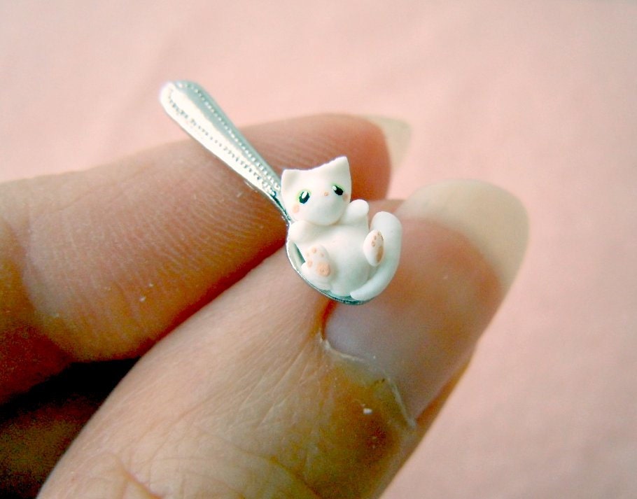 Tiny white kitten on a miniature dollhouse spoon