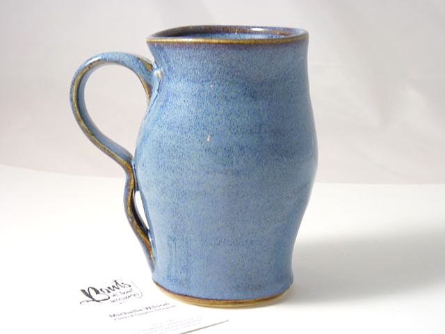 Tall mug glazed in textured blue glaze breaking brown