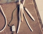 isis.  an white suede wrapped seabean with a fortune tellers hand necklace.