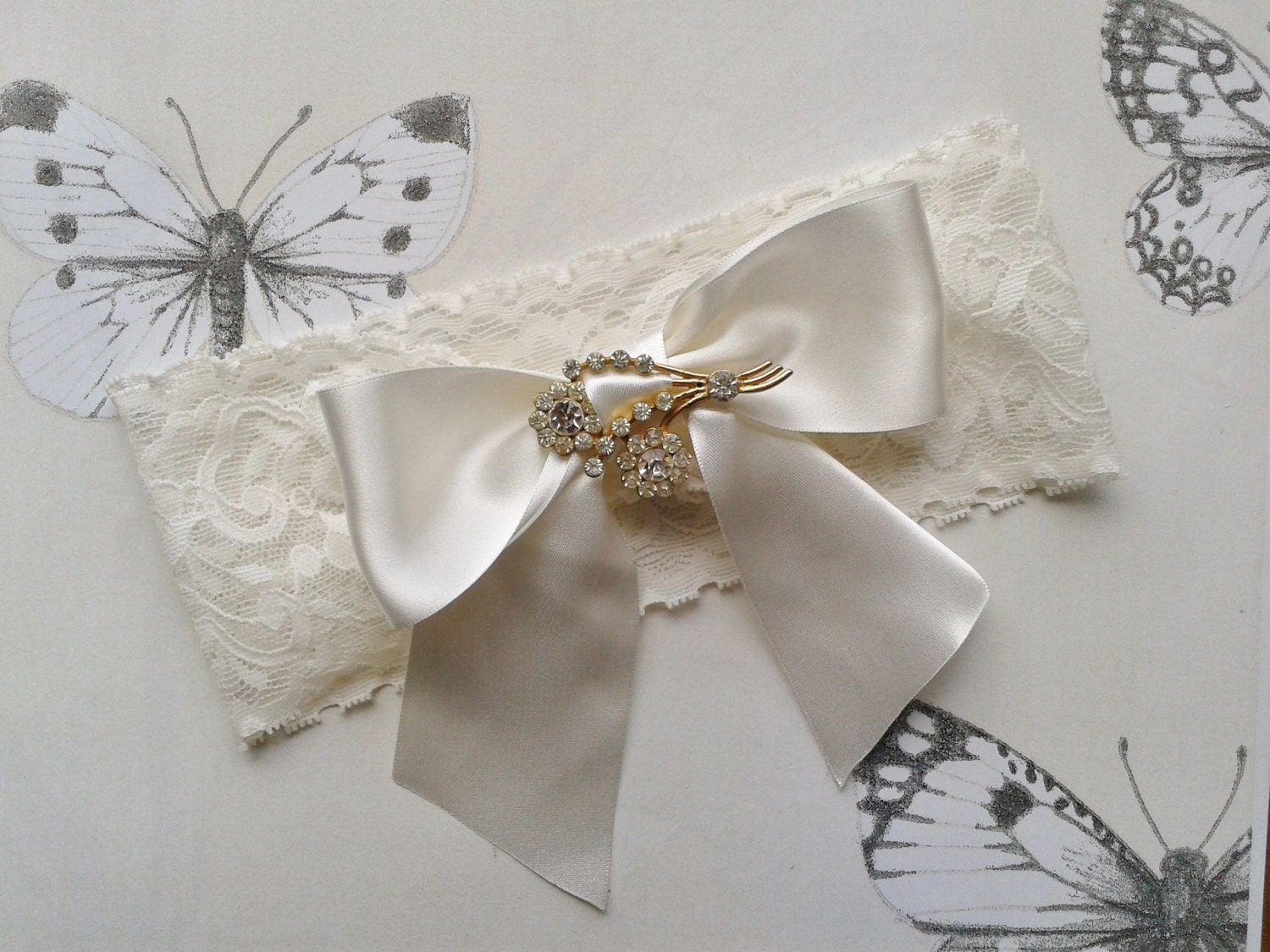 Ivory lace wedding garter with oversized ribbon bow and vintage brooch.