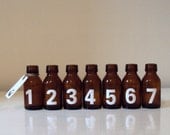 Seven amber apothecary bottles 1-7 / a luggage tag. Great typographics / Industrial decor