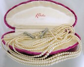 Eight strands of glorious graduated imitation or faux pearls. Just what you'd expect from a Mad Man era necklace, only more. I've seen a Richelieu ad with this exact case from 1948. In the original pink raspberry colored velvet clam shell presentation case with the Richelieu name. The necklace is unsigned and as per the original owner, it is the Richelieu that came in this presentation case. Pearls measure from 3 mm to 9 mm and are a creamy white color. Length is 16 inches with the extensions for the shortest strand of faux pearls. Fish hook clasp. Rhinestone bar is 1-1/2 inches long and silver colored, connecting all eight strands. All in excellent condition. A magnificent piece!