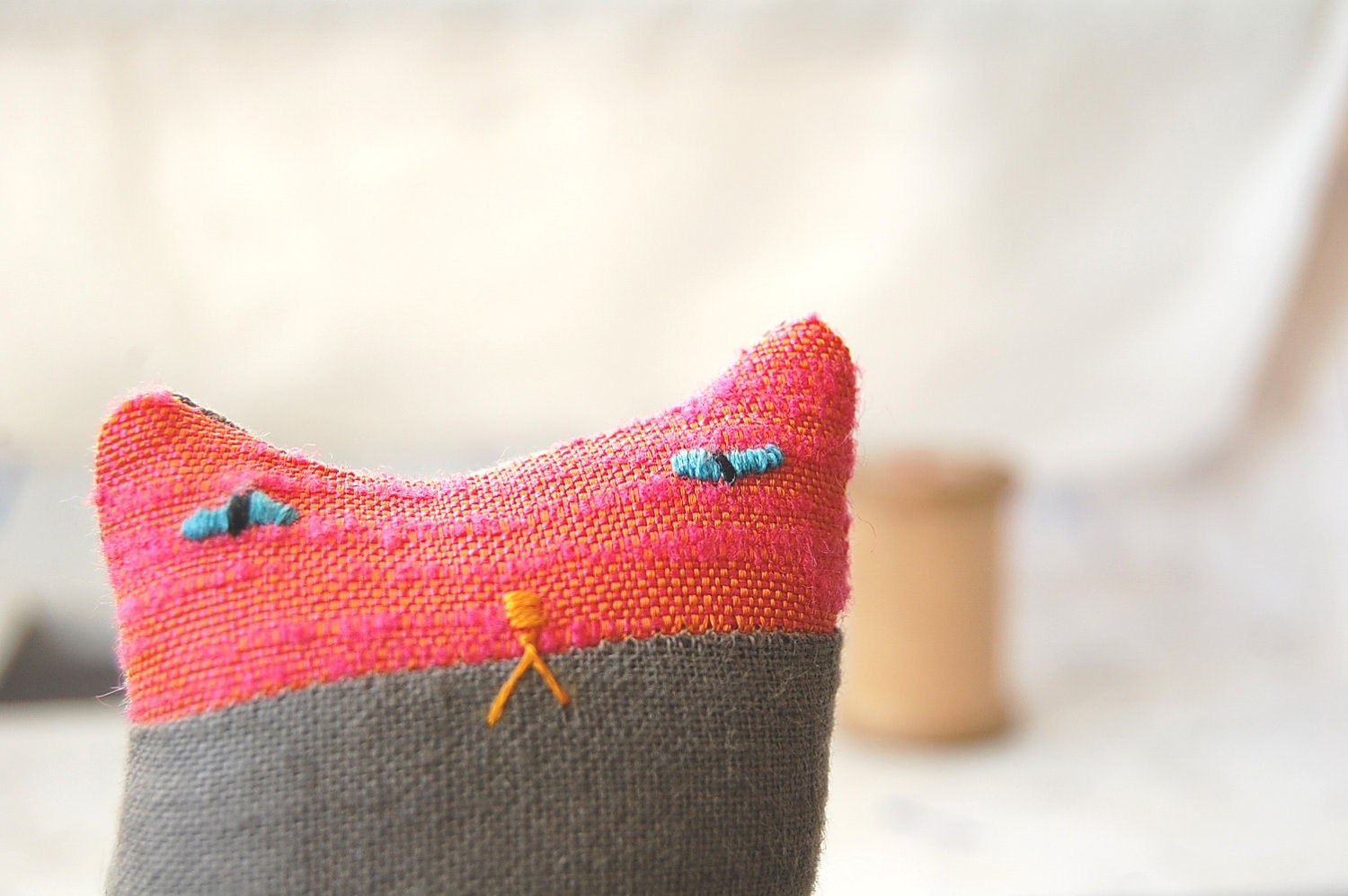 A small ornamental textile cat creature called Herb