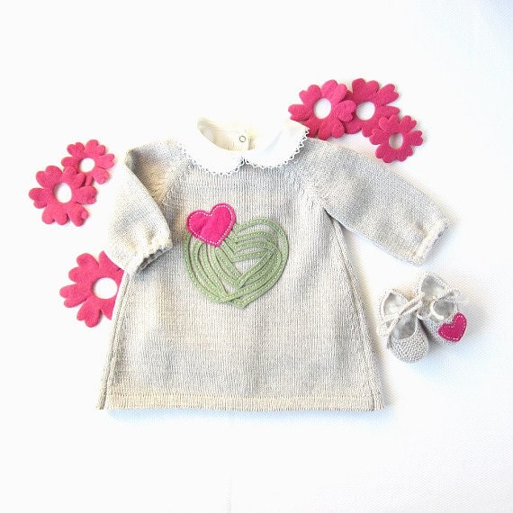 A knitted baby dress with felt hearts