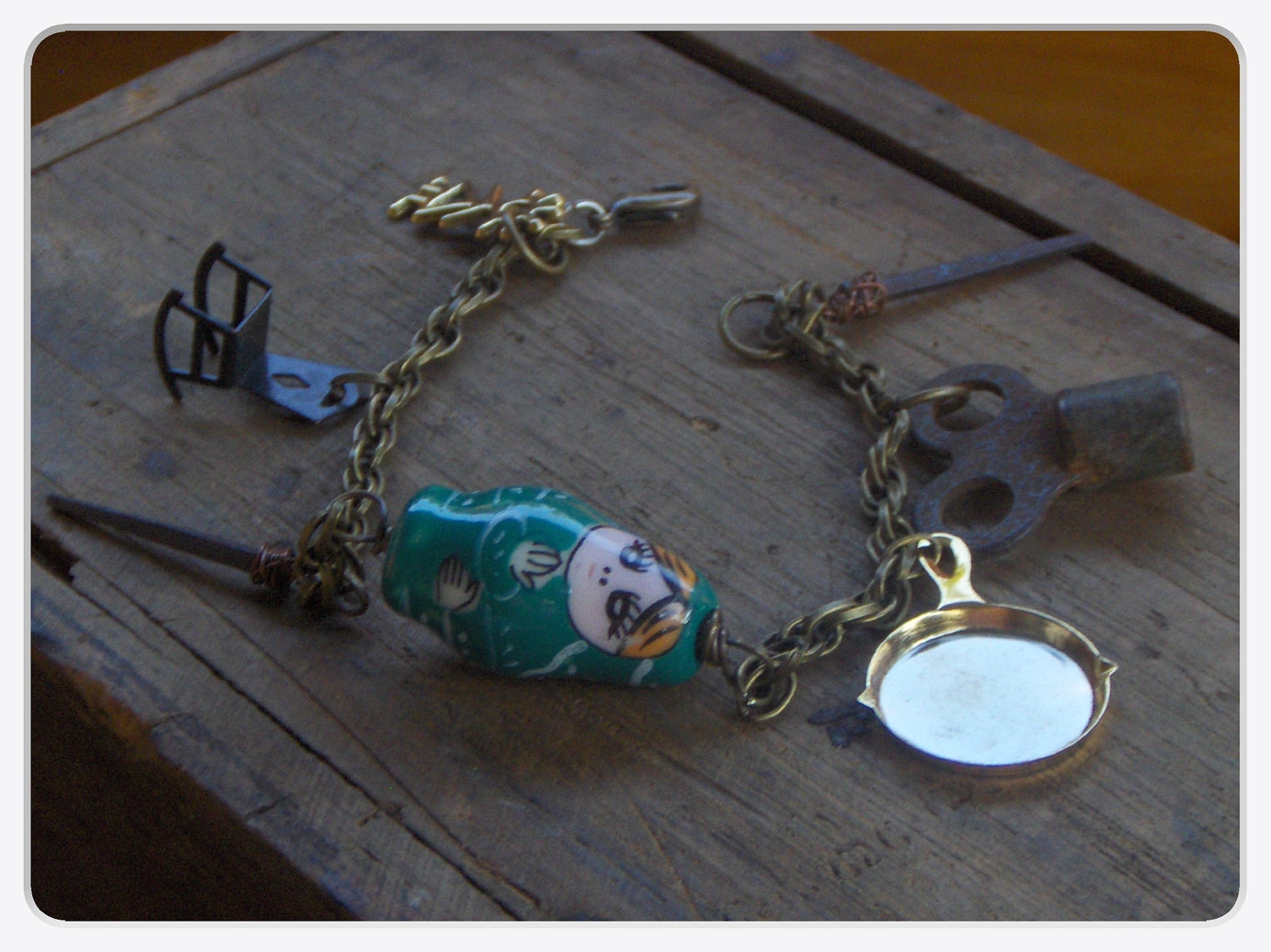 The Doll House Maker's Shop. Glass Matyroshka Babushka  doll, antique clock key, rusty antique doll house nails and trinket charm bracelet