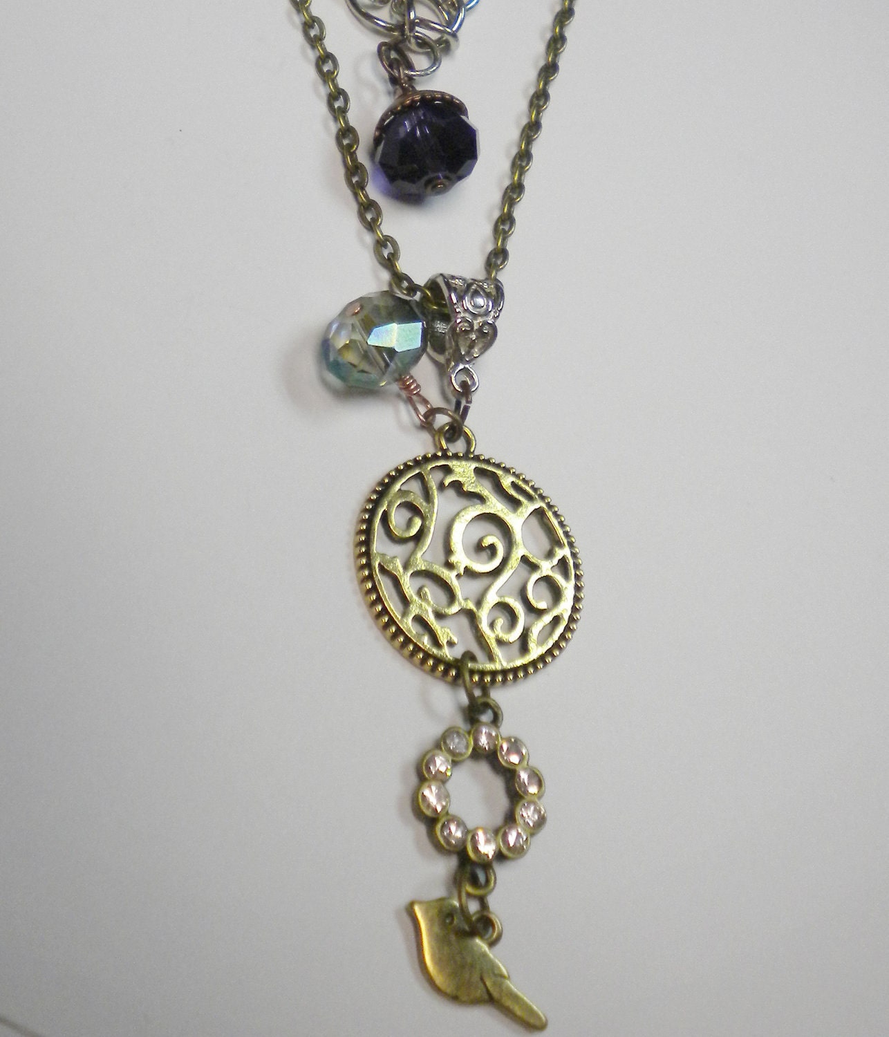 Long tri colored chain necklace with bird charm, gold swirl ring, czech pale blue crystal, purple crystal, rhinestone ring